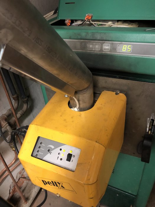En installerad Pellx-brännare från 2002 kopplad till en ctc CV35 panna, med synliga rör och reglage.