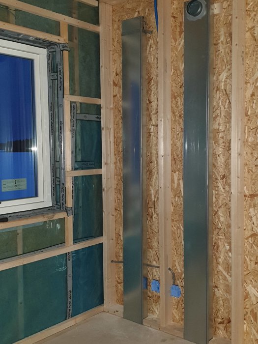 Ventilationsrör och elinstallationer i väggen av ett hus under konstruktion.