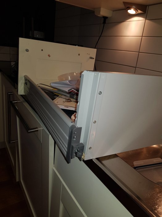 Köksskåpslucka öppen med synlig skruv, fråga om hur man avmonterar fronten.