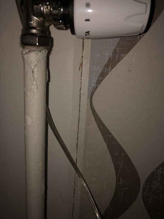 Radiator med synlig spricka i skarven på masonitskiva bakom elementet.