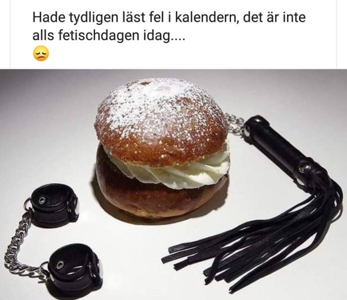 En semla bredvid handbojor och en piska, skämtsam jämförelse mellan fettisdagen och fetish.