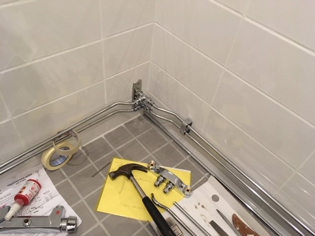 Välvda rör installerade i ett hörn med verktyg och byggmaterial på golvet.