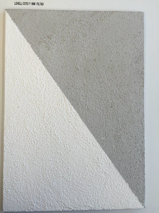 Hörna av en provyta med StoLevell Cote F puts i två finishar; slät på ena sidan och texturerad på den andra.