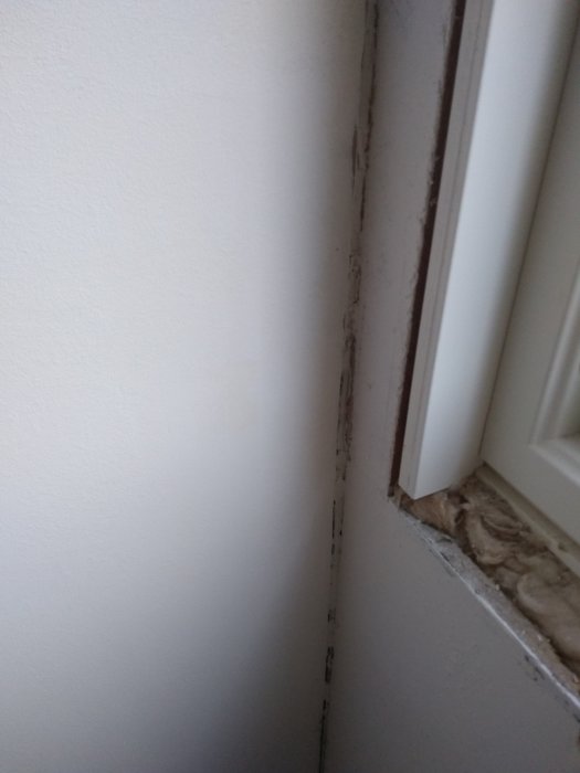 Glipa mellan vita masonitskivor i ett hörn innan renovering.