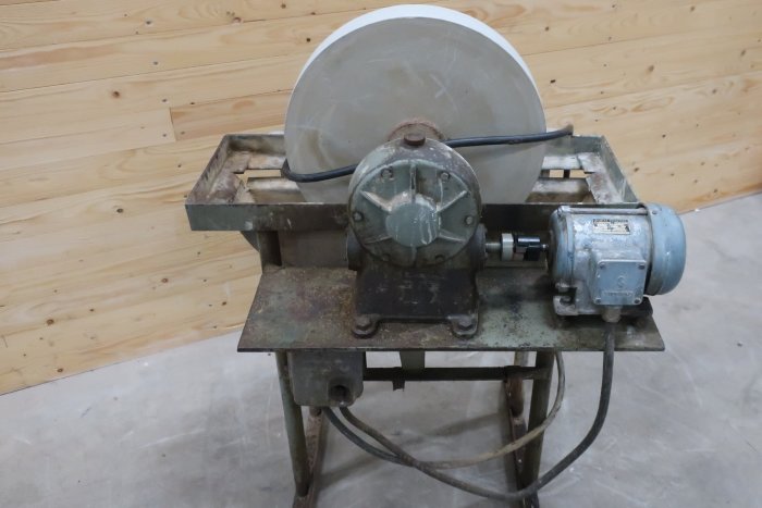 En betongblandare med en rund trumma och en elektrisk motor placerad på en metallram.