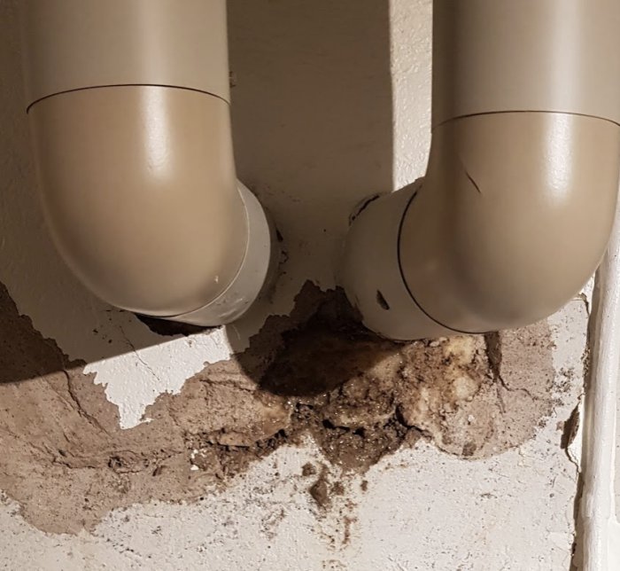Vattenskada vid rörgenomföring i en vägg, med poröst tätningsskum och avflagat ytskikt.