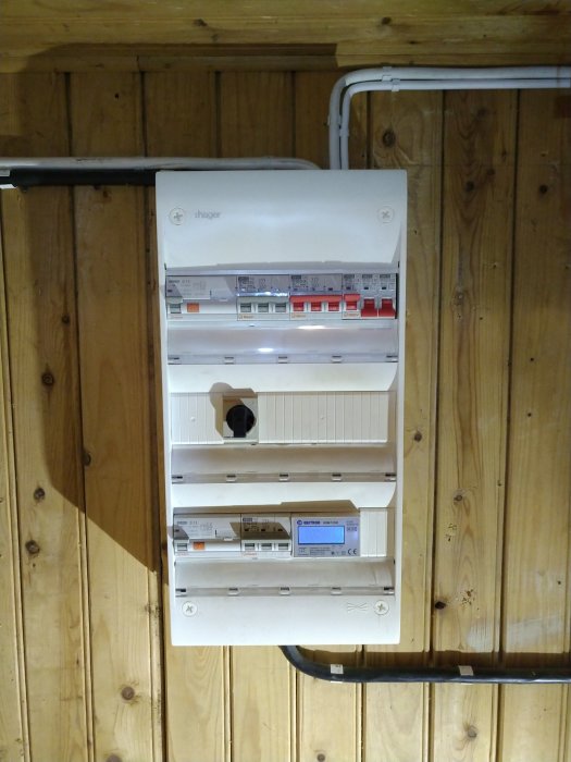 Nyinstallerad elektrisk central uppsatt på trävägg i källare med säkringar och anslutningar.