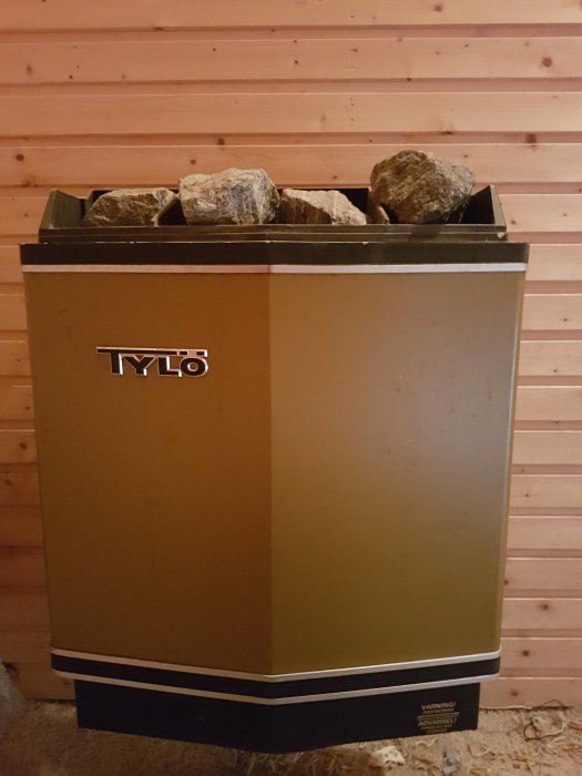 Tylö bastuaggregat i ett rum med träpanelväggar, fyllt med bastustenar, fråga om försäljning eller bortskänkning.