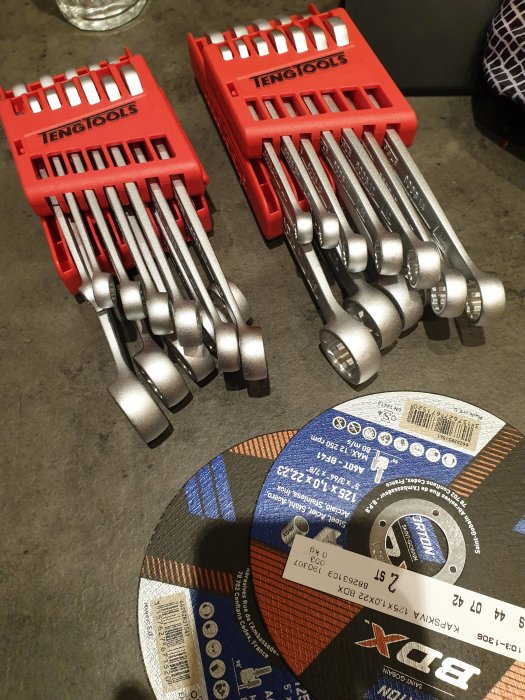 Två uppsättningar av Teng Tools blocknyckelsatser på bord med slipdiskar.