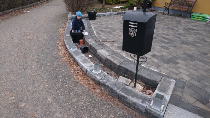 Stolpskor monterade på en ojämn stenmur med en person i bakgrunden.
