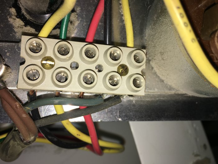Närbild på en elanslutning med flera kablar kopplade till en skruvplint i en elinstallation.