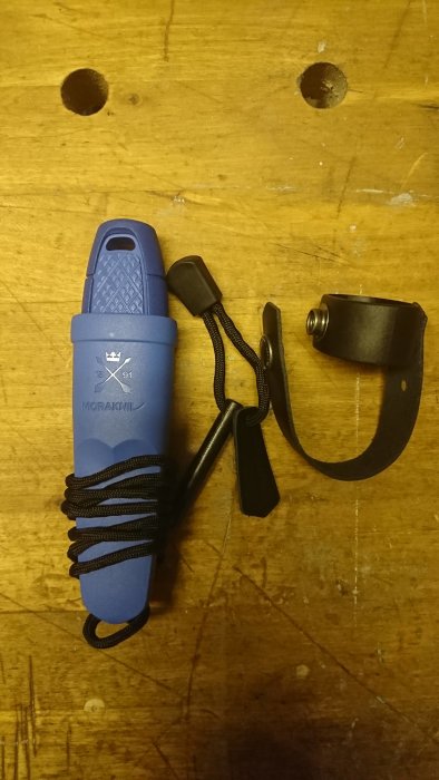 Blå Morakniv med slida och svart beltefeste på ett träbord.