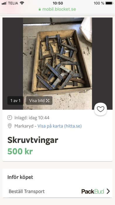 En samling använda skruvtvingar av metall i en träkasse.