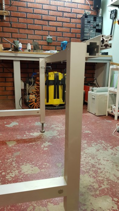 Modifierat bord med aluflex-skena och ikea-vinklar för sängben, i ett verkstadsrum.