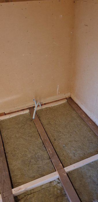 Renoverat rumshörn med ny stenullsisolering mellan träbjälklag, väggar med spånskivebeklädnad.