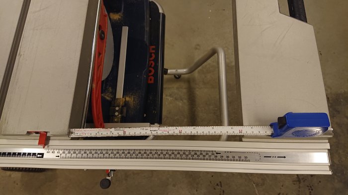 Måttband utsträckt bredvid ett sågbord för att visa måttangivelser.