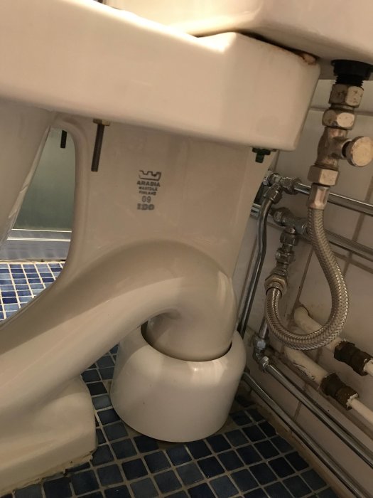 Gammal IDO wc-stol märkt "Arabia Finland 09 IDO", detaljbild som visar wc-stolens sida och röranslutningar.