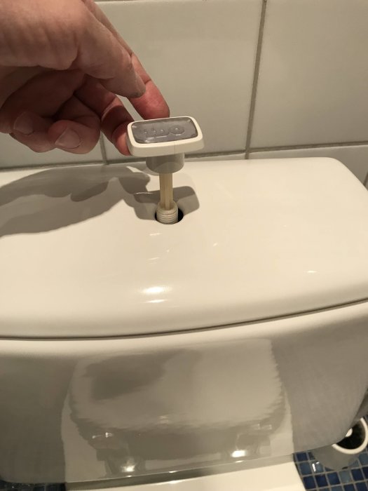 Person som håller i en IDO-toalettlocksknopp, söker plastlockmutter.