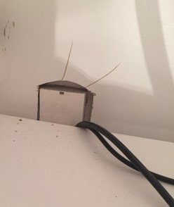 Elektriska kablar sticker ut från en vägg där en spis tidigare varit ansluten.