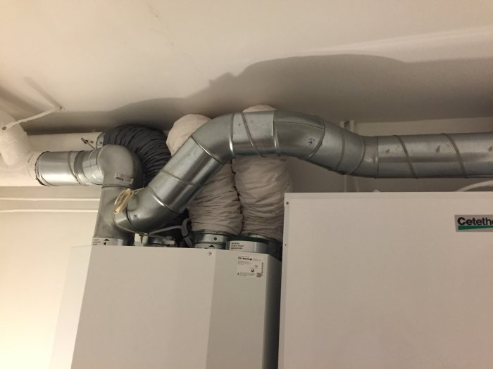 Nyinstallerat ventilationsaggregat i tvättstuga med synlig kondens längs rörledningar.