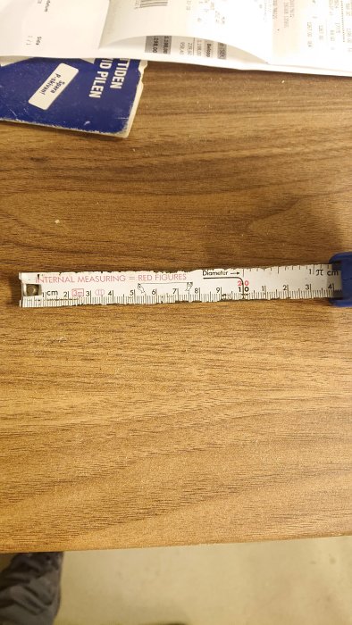 Måttband visar en mätning på cirka 139 mm på en träyta, med ett leende ansikte vid 139,5 mm.