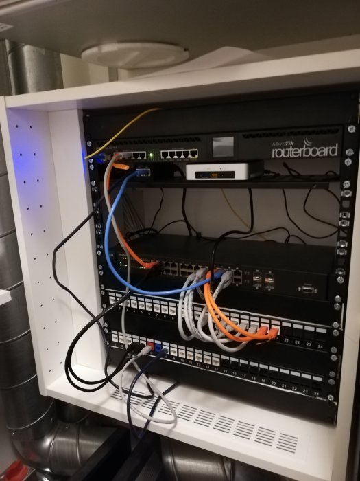 Ett hembyggt nätverksskåp med routers, switchar och patchpaneler monterade på rackskenor.