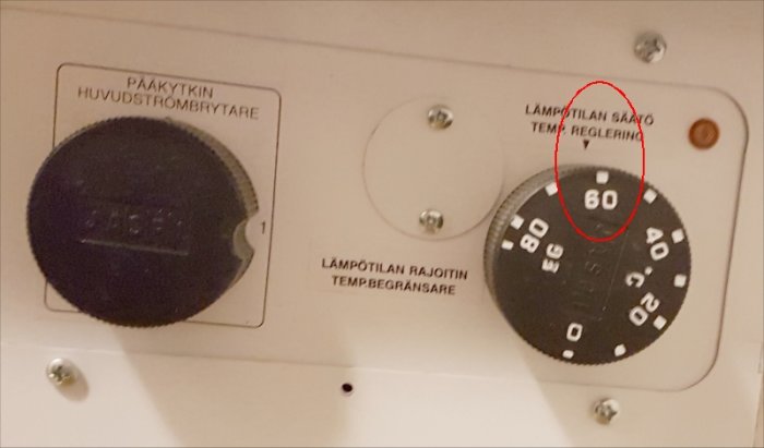 Varmvattenberedare termostat inställd på 60 grader Celsius, omgiven av reglerknappar.