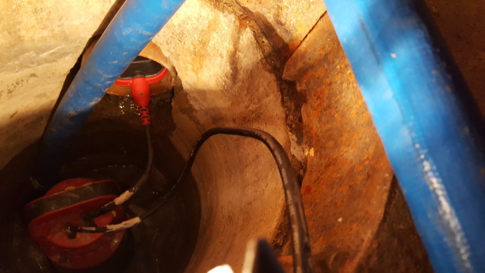 Pump i en översvämmad brunn med rör i källare, trolig anslutning till dränering från 1979.