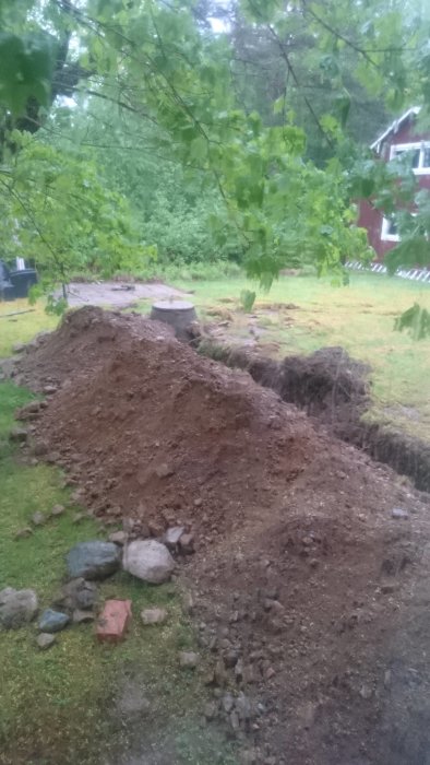 Uppgrävd mark och naturstensgrund vid planerat byggprojekt för utbyggnad.