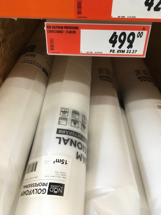 Rullar med vit XPS golvunderlägg på butikshylla, etiketterad för isolering med priset överst.