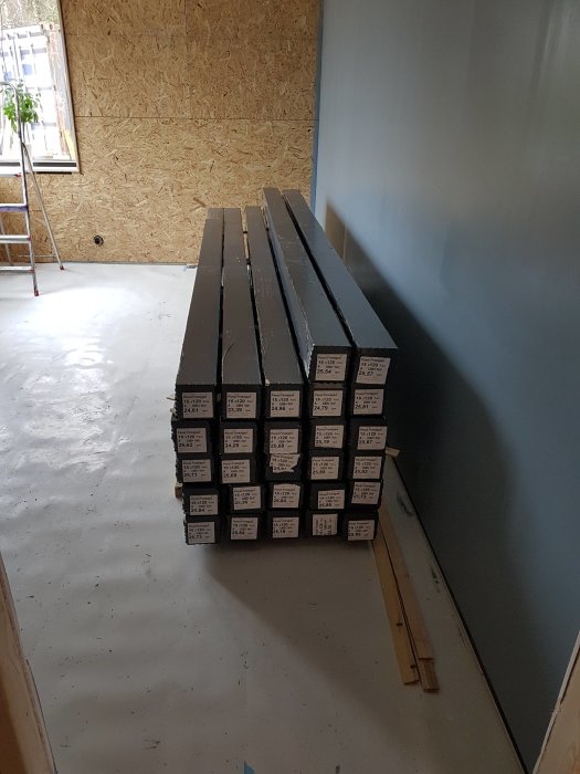 Obhandlad spontad panel levererad i buntar i ett rum under renovering med OSB-skivor och målade väggar.