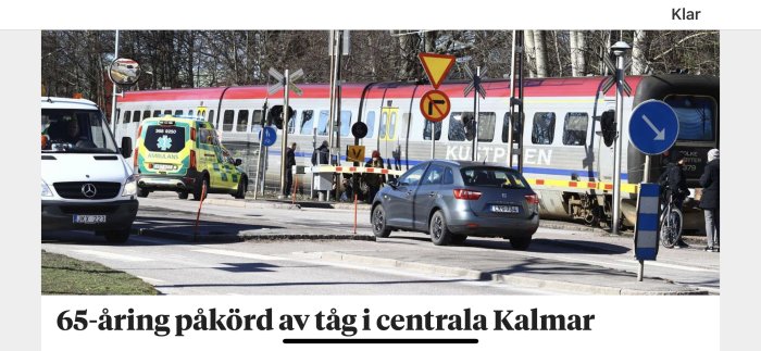 Olycksplats med ambulans och tåg vid nedfällda bommar, efter att en person blivit påkörd.