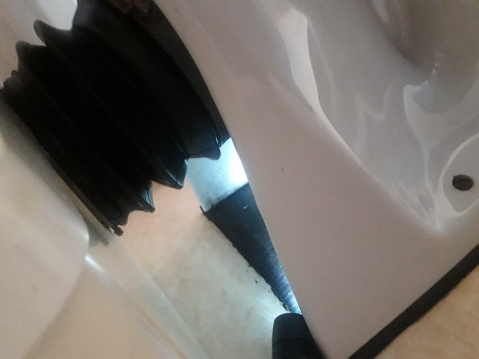 Närbild på toalett med svart matta limmad på golvet och vattenlåsets "bubbla" synlig.