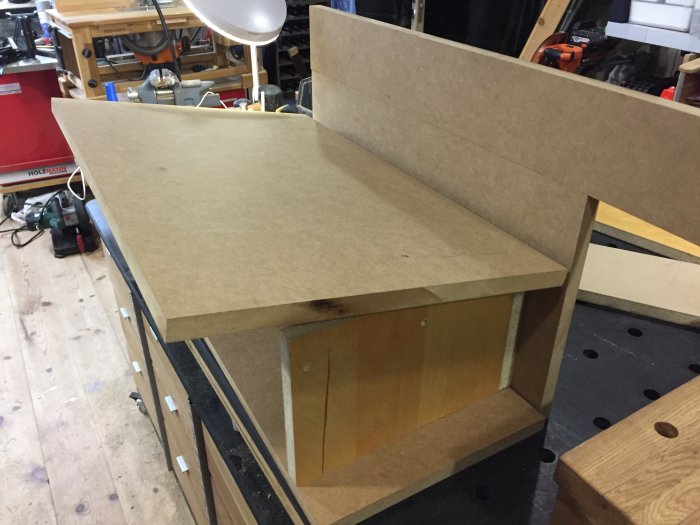 Prototyp av fräs i MDF-material på verkstadsbänk med verktyg och utrustning i bakgrunden.
