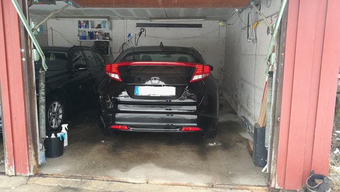 Svart Honda Civic Sport -12 parkerad i ett garage med öppna portar och några rengöringsmedel vid sidan.