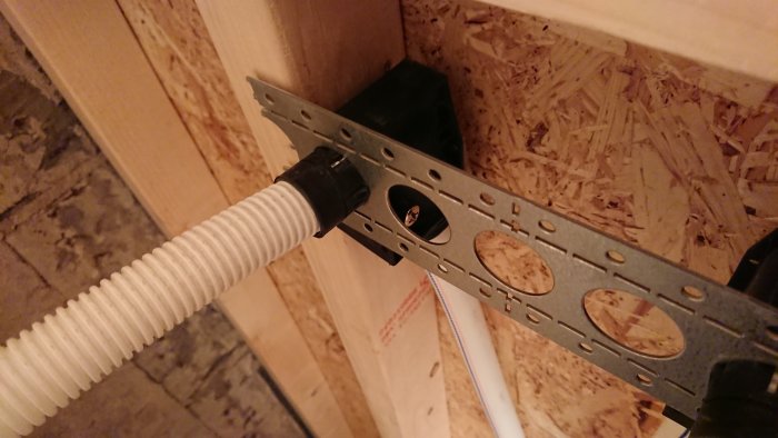 Installation av VVS-fäste med genomgående hål mot en trävägg med synlig regel.