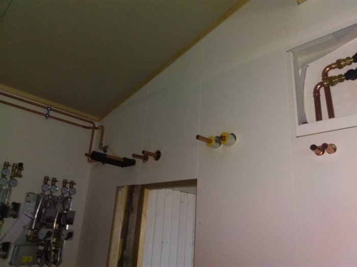 Installationsvy av kopparledningar och rörsystem i ett hus under renovering.