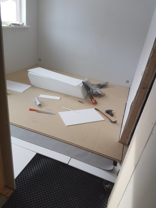 Sovrum under renovering med pågående golvinstallation och verktyg utspridda.