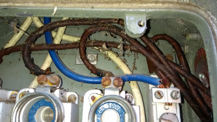 Äldre elskåp med pappersisolerade ledningar och korroderade anslutningar.