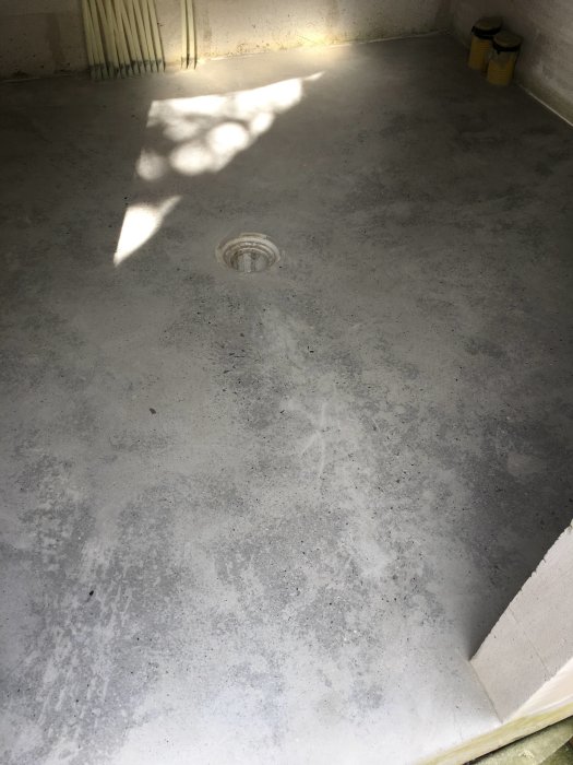 Nyslipad betonggolv med ojämn yta och ett avlopp i mitten efter ett par timmars arbete.