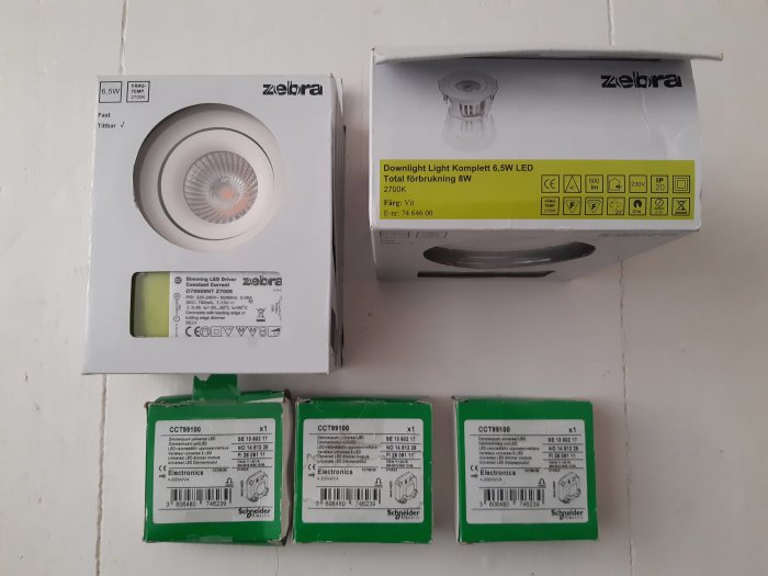 Zebra 6,5W LED downlights och Schneider dimmerpuckar på ett bord, oanvända i förpackningar.