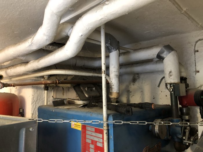Isolerade rör över en gammal värmepanna som ska bytas ut.
