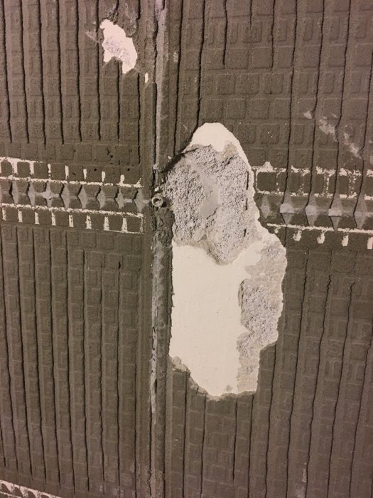 Sliten vägg med synlig lättbetong och rester av gammal fix, fråga om renoveringsmetod.