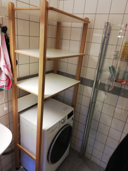 Trähylla av massiv ek och björkplywood över en tvättmaskin i ett kaklat badrum.