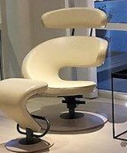 Vit modern fåtölj med unik design i utställningsmiljö.