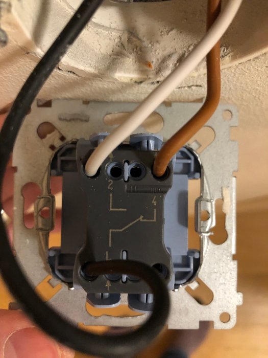 Närbild av en öppen korsbrytare med synliga ledningar och anslutningar i en vägginstallation.