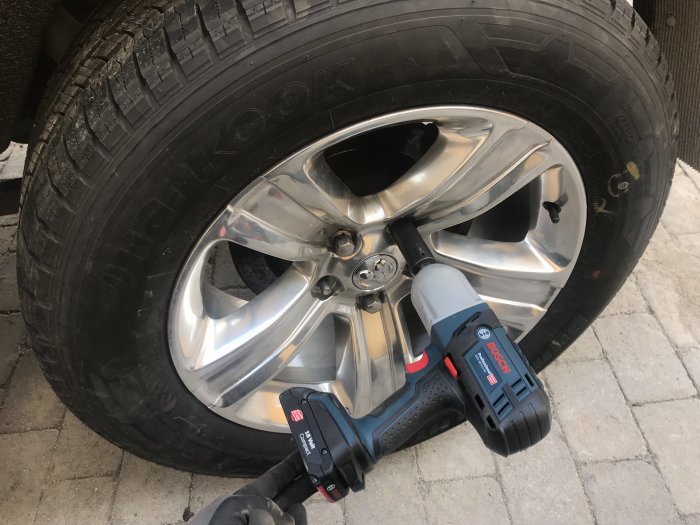 Batteridriven slagskruvdragare vid ett bilhjul under hjulbyte.
