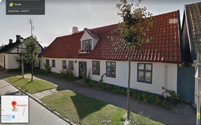 Välvårdat enfamiljshus med tegeltak, vita väggar, blomsterlådor och en gångväg sett i Google Street View.