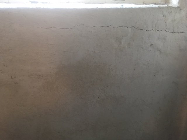 Spricka högst upp på en smutsig betongvägg i ett verktygsförråd.