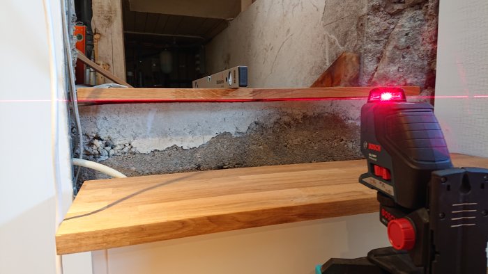 Renovering av trappa med laser för att fixa ojämnheter i betong och nytt trästeg.
